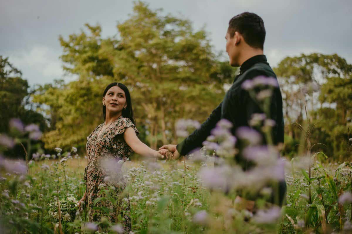 a couple holding hands and walking on a grass field